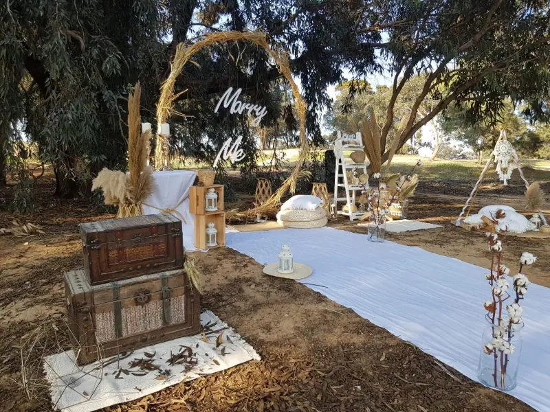 חישוק עץ עם שלט Marry Me, שטיח לבן ותיבת עץ עתיקה בטבע